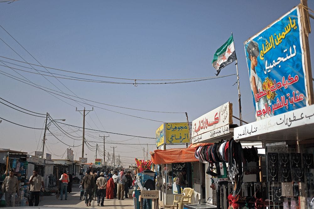 Syrian refugees and aid workers mix on a market street in Zaatari in April 2014