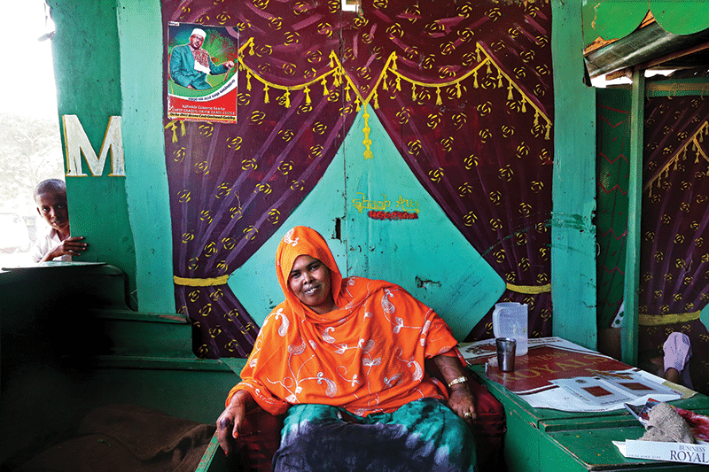 Khat queen Kaltuna Ismail Kabadhe in her outlet. Kaltuna is one of the first women to gain influence in the male-dominated world of politics, and hangs campaign posters for local candidates in her stalls
