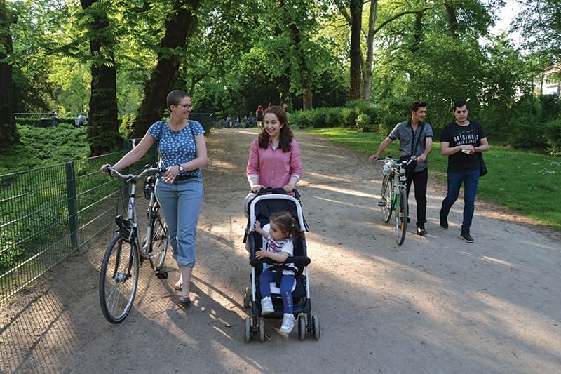 German volunteer Alexandra Einmahl and Joud Na from Aleppo, Syria, walk to a Start With a Friend group picnic in Cologne’s Volksgarten on 11th May. Photo: Matthew Lee