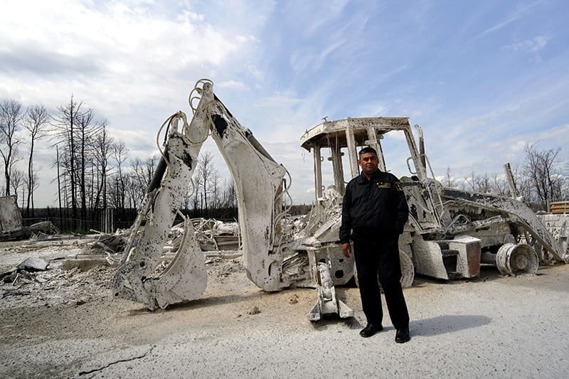 Security guard Mohammed Sadiki guards the ashen remains of the Centennial Park section of Fort McMurray