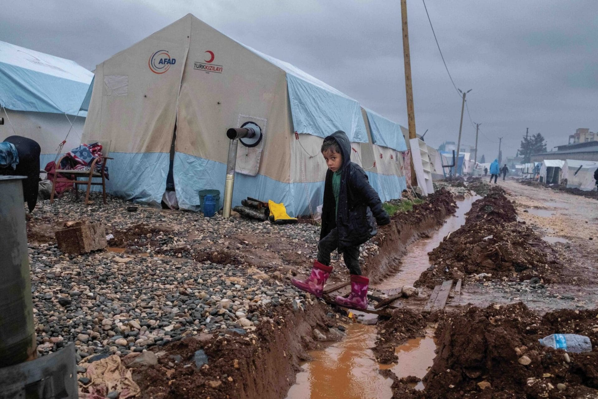 A child crosses a ditch to reach tents set up to house people displaced by the earthquakes in Adiyaman, 25th March 2023