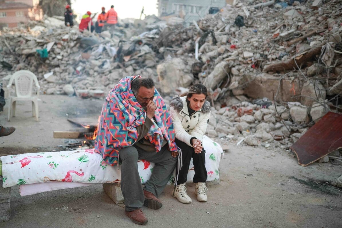 Earthquake victims sit among the damage in Hatay, Turkey. Within a week of the 6th February earthquakes the death toll in Turkey and Syria was over 35,000 people