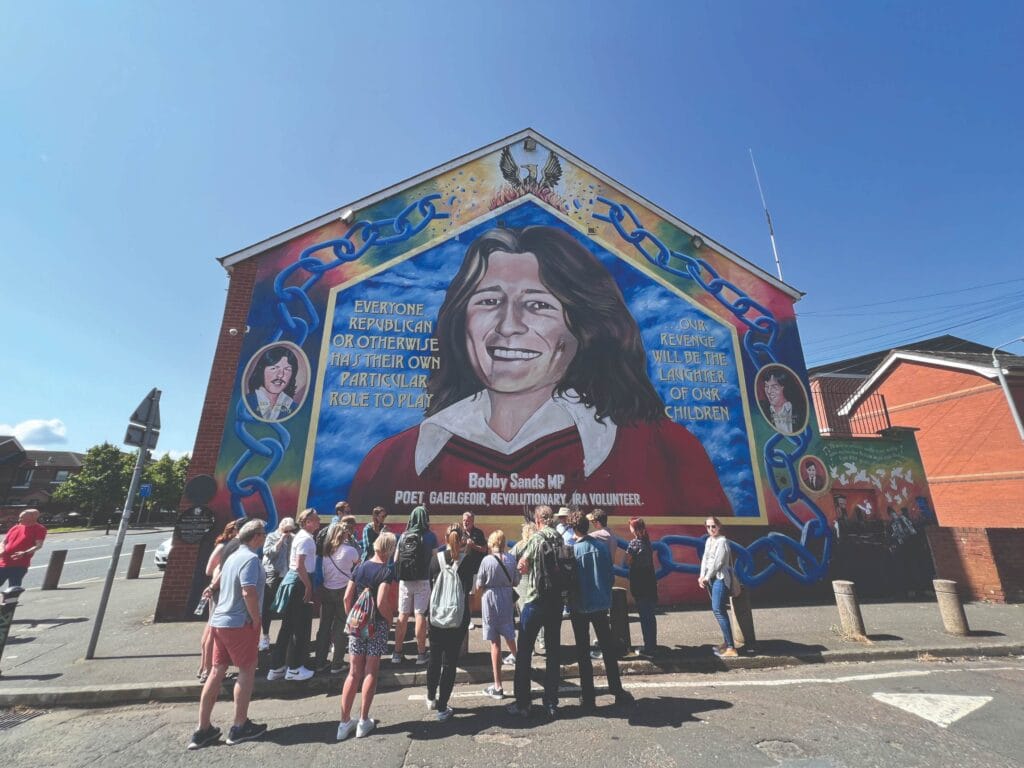 A tour group gathers in front of the Bobby Sands mural in the Falls Road area of Belfast. Sands was the first Republican prisoner to die in a 1981 hunger strike